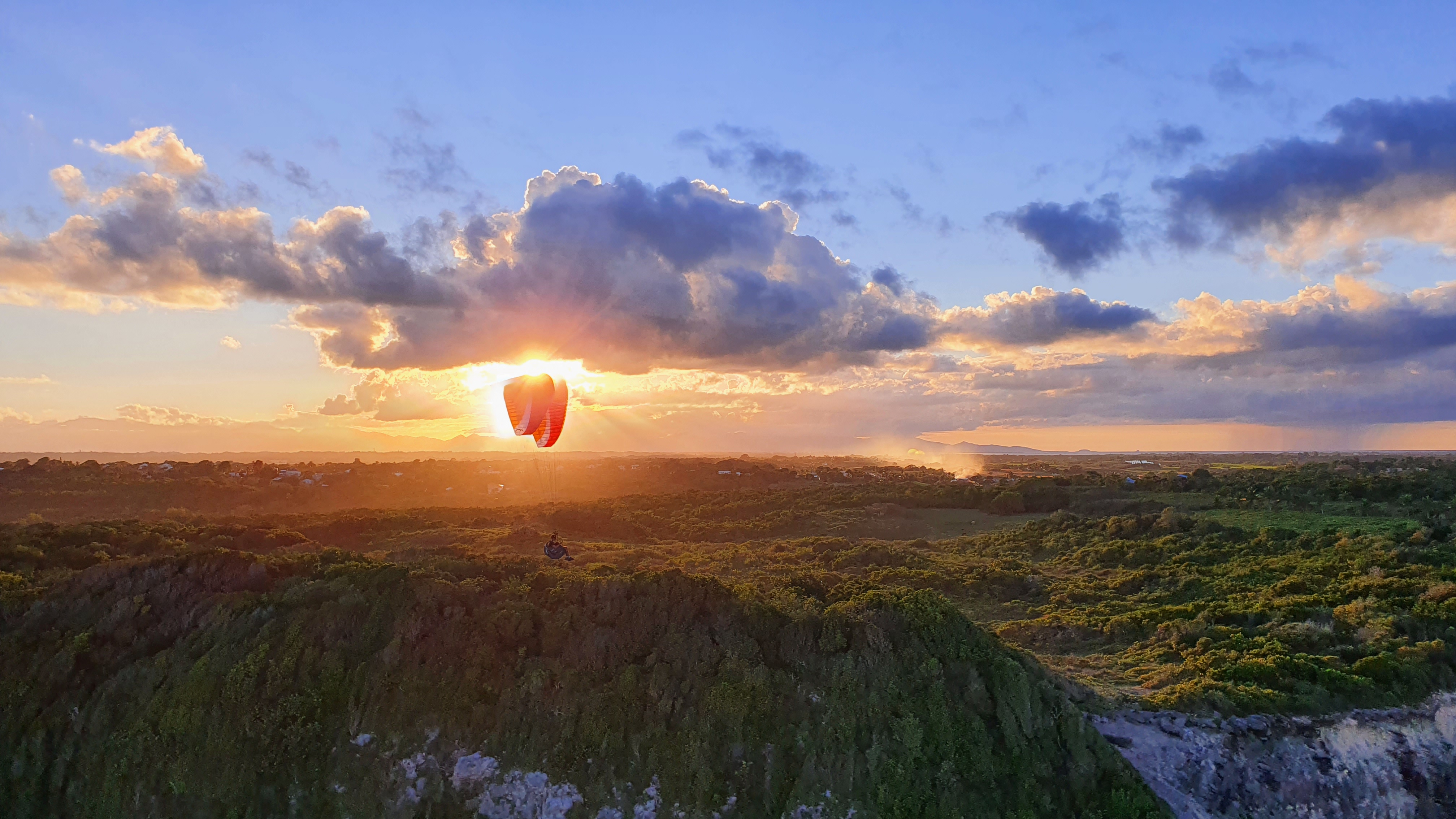 Parapente volant au coucher du soleil dans un paysage découvert en voyage